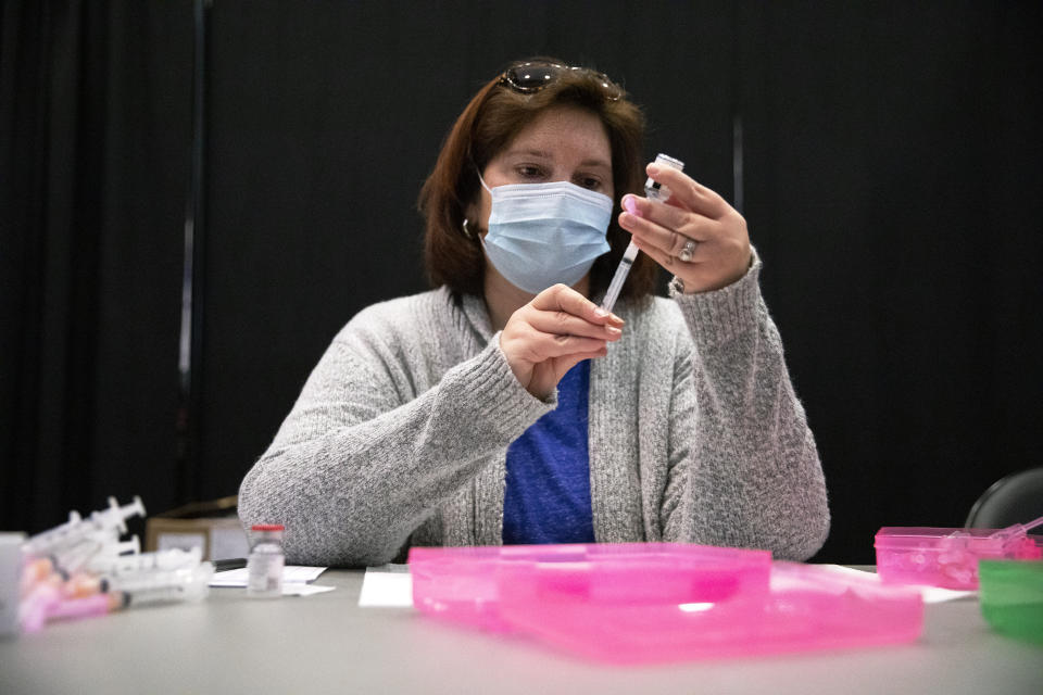 A healthcare professional works to fill syringes with doses of the Moderna COVID-19 vaccine at Pinnacle Bank Arena on Friday, Jan. 22, 2021 in Lincoln, Neb. (Kenneth Ferriera/Lincoln Journal Star via AP)