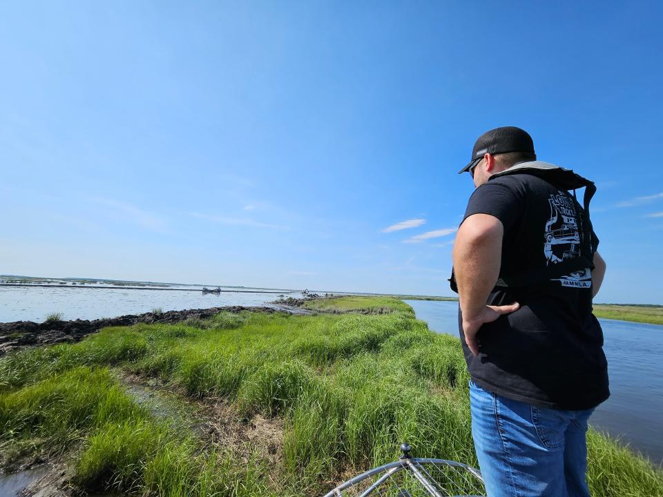 Josh Guerra, 35, of Hopedale St. Bernard, stands on the fan's cage of an airboat overlooking part of the $114 million Lake Borgne marsh restoration project by CPRA, May 16, 2024.