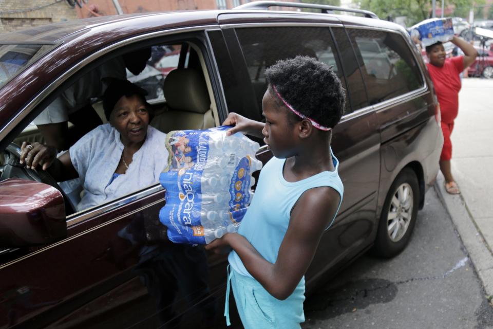 Elaine Younger, 11, and Tahvion Williams, 14, right, load water in their family's van at the Newark Health Department in Newark, N.J., Wednesday, Aug. 14, 2019. Residents began picking up bottled water on Monday, days after elevated lead levels were found in homes where city-issued filters had been distributed months ago as part of an ongoing effort to combat contamination. (AP Photo/Seth Wenig)