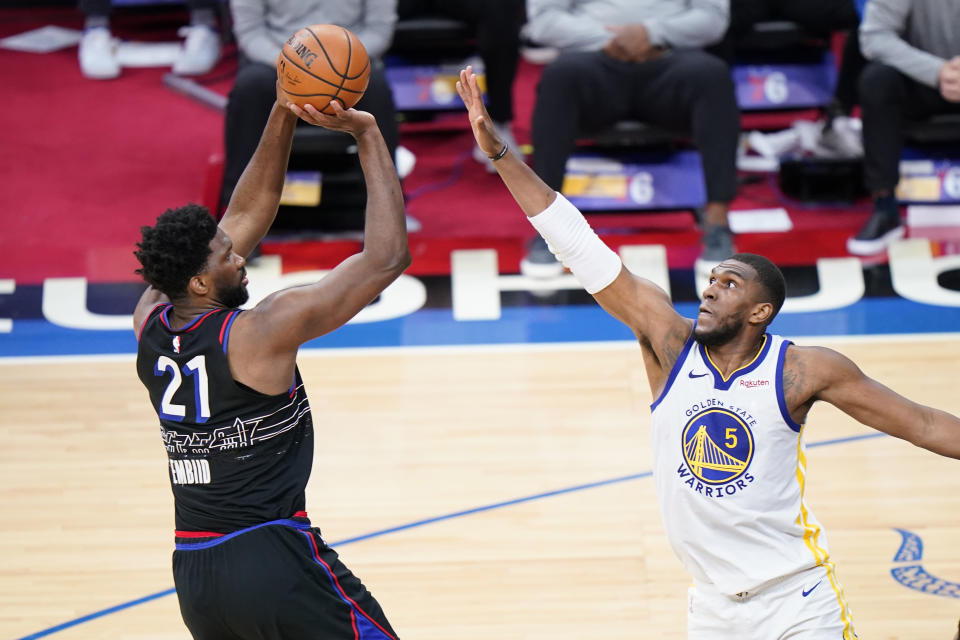 Philadelphia 76ers' Joel Embiid, left, goes up for a shot against Golden State Warriors' Kevon Looney during the second half of an NBA basketball game, Monday, April 19, 2021, in Philadelphia. (AP Photo/Matt Slocum)