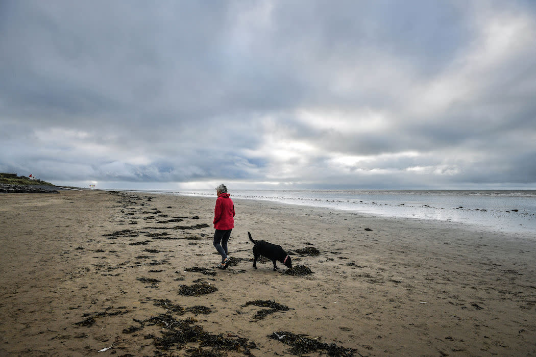 A woman walks her dog on Pendine Sands, Camarthenshire, as forecasters have downgraded warnings that Storm Helene could pose a risk to life when it hits this week (Picture: PA)