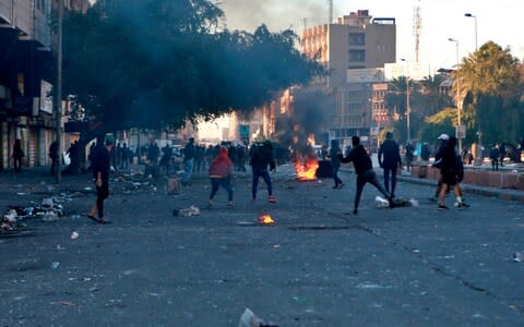 Protesters set fire to close a street during clashes between security forces and anti-government protesters near Baghdad's Khilani square - Credit: AP