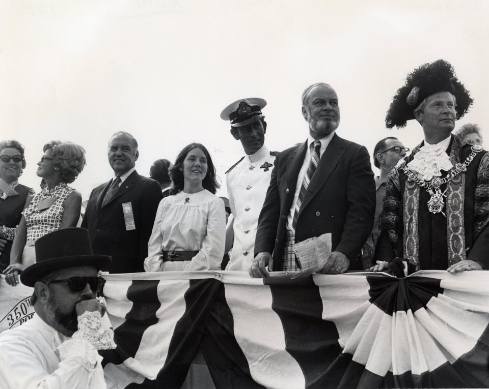 Wearing his Royal Navy uniform, Prince Charles stands at the reviewing stand for Portsmouth's 350th anniversary parade. To his right are Mayor Arthur Brady Jr. (with beard) and Portsmouth, England Lord Mayor John P.N. Brogden in ceremonial dress.