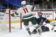 Minnesota Wild left wing Zach Parise, left, scores a goal against Colorado Avalanche goaltender Philipp Grubauer in the second period of an NHL hockey game Wednesday, Feb. 24, 2021, in Denver. (AP Photo/David Zalubowski)