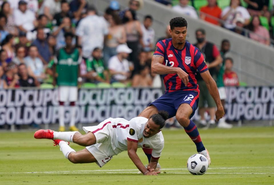 Jul 29, 2021; Austin, Texas, USA; Qatar forward Akram Afif (11) falls to the ground as United States defender Miles Robinson (12) dribbles past in the first half of a Concacaf Gold Cup semifinal soccer match at Q2 Stadium.