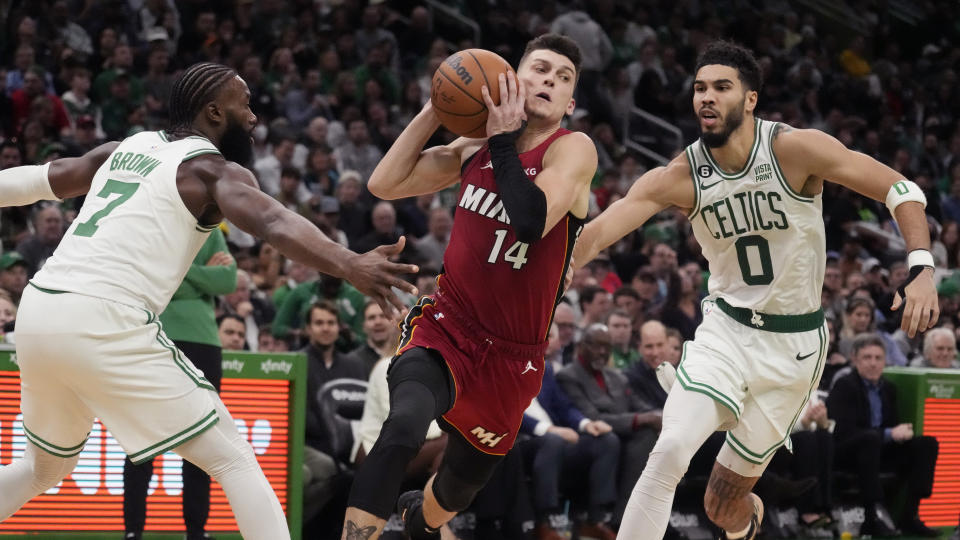 Miami Heat guard Tyler Herro (14) tries to drive between Boston Celtics guard Jaylen Brown (7) and forward Jayson Tatum (0) during the second half of an NBA basketball game Wednesday, Nov. 30, 2022, in Boston. (AP Photo/Charles Krupa)