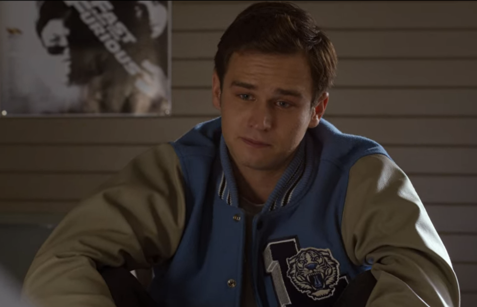 a teenage boy sitting down and looking thoughtful