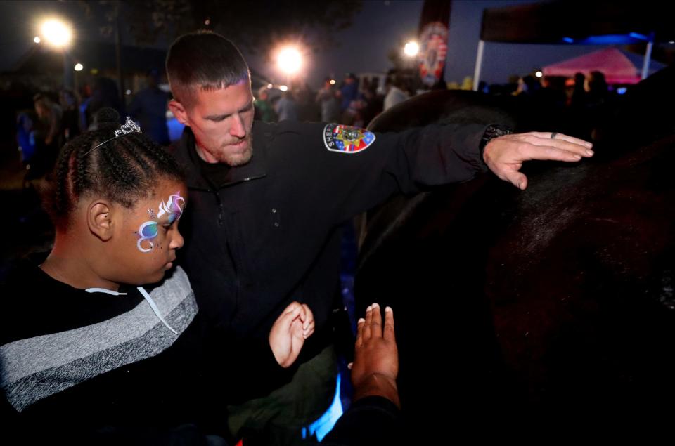 Sgt. Jamie Holloway with the Rutherford County Sheriff's Department encourages Journee Cook, 14, to pet one of the Sheriff Department's horses, Big Momma, during the National Night Out in La Vergne, on Tuesday, Oct. 4, 2022, at Veterans Memorial Park.