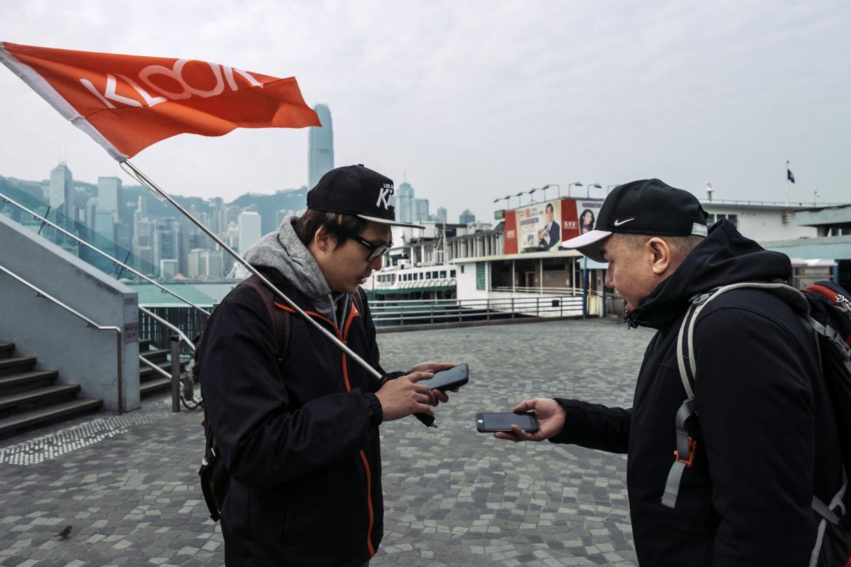 A tour guide, left, scans a quick response (QR) code on a tourist's smartphone during a guided walking tour hosted by Klook Travel Technology Ltd. in Hong Kong, China, on Wednesday, Feb. 7, 2018. 