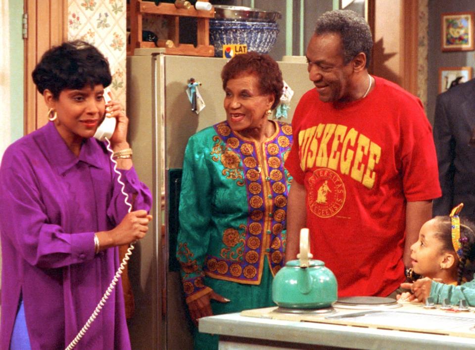 FILE - In this 1992 file photo originally released by NBC, Phylicia Rashad, portraying Clair Huxtable, left, talks on the telephone while Clarice Taylor, portraying Anna Huxtable, center, and Bill Cosby, portraying Dr. Cliff Huxtable and Raven Symone portraying Olivia, right, look on in a scene from "The Cosby Show." Why settle for one great mom when, as any TV viewer knows, you can adopt a series of them? AP Television Writer Lynn Elber chooses five of the best sit com moms, from the demure 1950s version to the freewheeling 21st-century incarnation. The character of Clair Huxtable remained a calm center of a whirlwind of activity, while tending to a legal career and caring for her five children and "big kid" husband. (AP Photo/NBC, file)