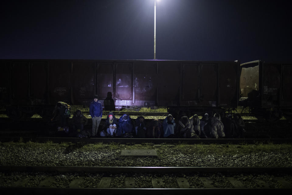 In this picture taken Monday Dec. 16, 2019, a group of migrants wait to be identified after being detained by Bosnian police around the the river Drina bordering between Bosnia and Serbia in the town of Karakaj, northeastern Bosnia.(AP Photo/Manu Brabo)