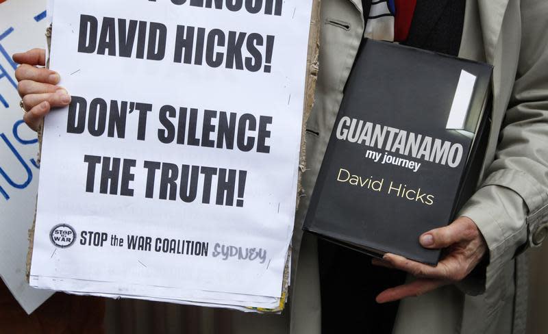 A supporter of former Guantanamo Bay inmate Australian David Hicks holds a copy of his book during a protest outside the Supreme Court in Sydney August 3, 2011. REUTERS/Tim Wimborne