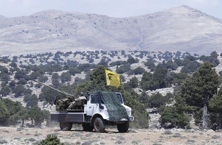 Lebanon's Hezbollah fighters sit on a pick-up truck mounted with a weapon and decorated with a flag depicting assassinated Hezbollah military commander Imad Moughniyah in Khashaat, in the Qalamoun region after they advanced in the area May 15, 2015. REUTERS/Mohamed Azakir