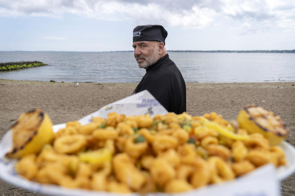 Executive chef John Bordieri is photographed with a dish of calamari outside Iggy's Boardwalk restaurant Friday, June 7, 2024, in Warwick, R.I. This year, the "calamari comeback" chef might not be coming back. Bordieri became known as the "calamari ninja" for standing wordlessly, clad head-to-toe in black, and holding a platter of sauteed squid during a video roll call of states that nominated Joe Biden during the 2020 Democratic National Convention. But he now says he hasn't heard from state or national leaders about a repeat performance at this summer's party's convention in Chicago. (AP Photo/David Goldman)