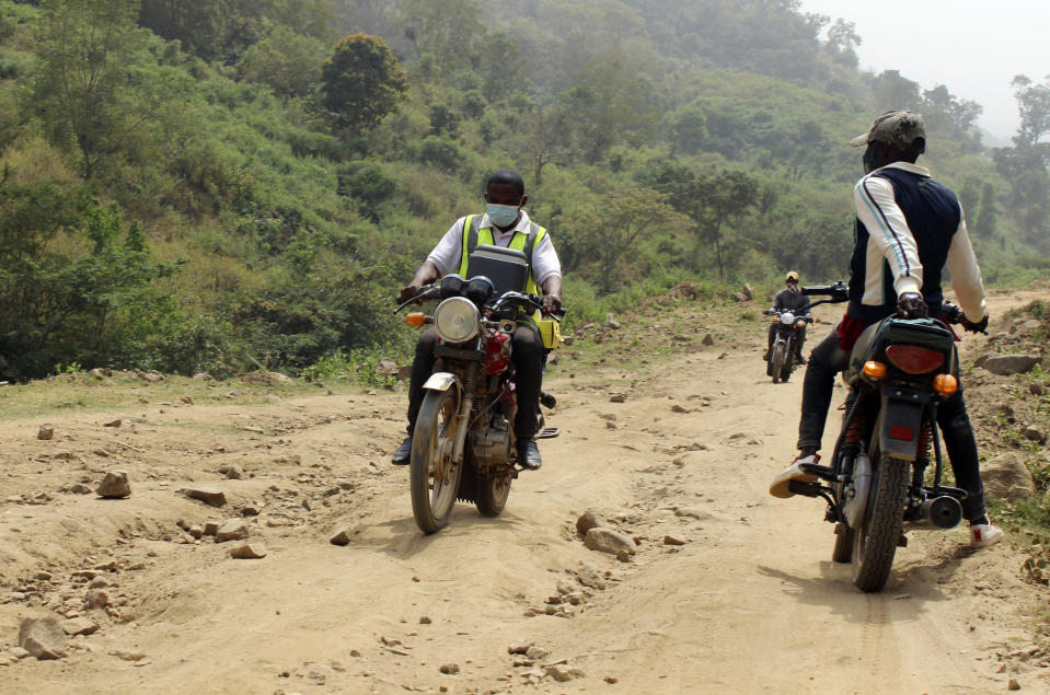 Yunusa Bawa, a community health worker, rides on a motorbike with a box of AstraZeneca coronavirus vaccines, in Sabon Kuje on the outskirts of Abuja, Nigeria, Monday, Dec 6, 2021. As Nigeria tries to meet an ambitious goal of fully vaccinating 55 million of its 206 million people in the next two months, health care workers in some parts of the country risk their lives to reach the rural population. (AP Photo/Gbemiga Olamikan)