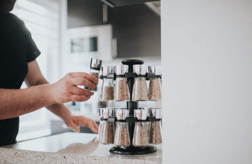 man taking a jar off a spice rack