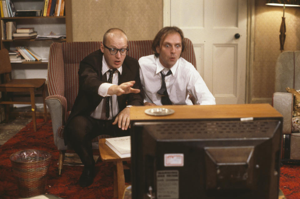 Comic actors Adrian Edmondson (left) and Rik Mayall watching television in scene from episode 'Contest' of the BBC television sitcom 'Bottom', June 24th 1990. (Photo by Don Smith/Radio Times/Getty Images)