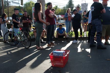 A Trader Joe's cart left by a customer who fled a hostage situation in the store sits in a parking lot nearby where employees and others wait for police to clear the scene in Los Angeles, California, Saturday July 21, 2018. REUTERS/Andrew Cullen