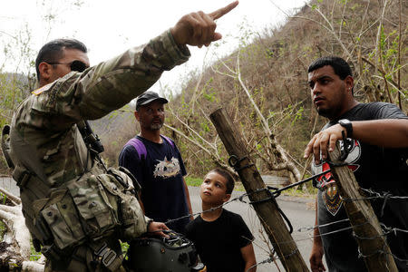 Pilot Eldwin Bocanegra Torres speaks with residents isolated by landslides in the mountains after unloading water and food from a helicopter during recovery efforts following Hurricane Maria, near Utuado, Puerto Rico, October 10, 2017. REUTERS/Lucas Jackson