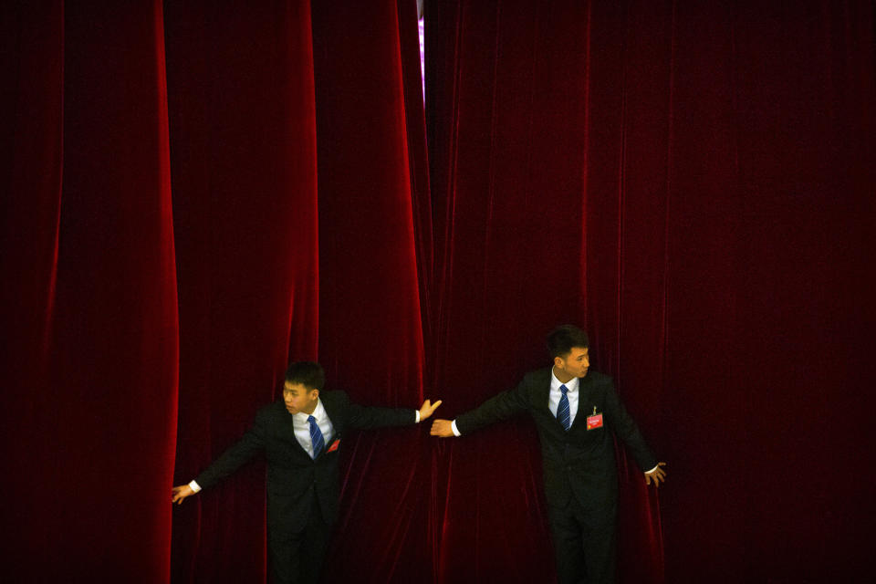 FILE- In this March 15, 2018, file photo, security officials try to keep a curtain closed as delegates leave after the closing session of the Chinese People's Political Consultative Conference (CPPCC) at the Great Hall of the People in Beijing. Thousands of delegates from around China are gathering in Beijing for annual session of the country's rubber-stamp legislature and its advisory body, an event characterized more by the authoritarian ruling Communist Party leadership's desire to communicate its message than any actual discussion or passage of laws. (AP Photo/Mark Schiefelbein, File)