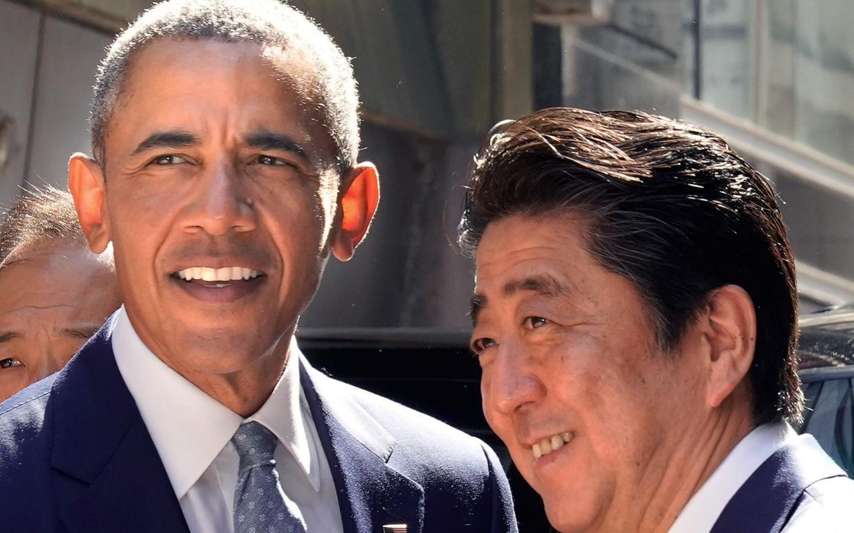 Former US president Barack Obama (L) is greeted by Japan's Prime Minister Shinzo Abe in front of a sushi restaurant in the Ginza shopping district of Tokyo - AFP