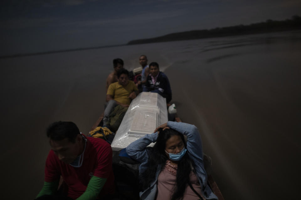 Relatives accompany the coffin that contains the remains of Jose Barbaran who is believed to have died from complications related to the new coronavirus, as they travel by boat on Peru's Ucayali River, Tuesday, Sept. 29, 2020. Despite the risk, family members decided to travel by night to Barbaran's hometown of Palestina, a four-hour journey. (AP Photo/Rodrigo Abd)