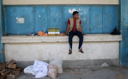 A Palestinian man sits next to food supplies at an aid distribution center run by United Nations Relief and Works Agency (UNRWA) in Khan Younis in the southern Gaza Strip September 1, 2018. REUTERS/Ibraheem Abu Mustafa