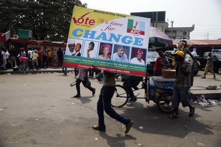 A man carries a banner campaigning for All Progressives Congresses candidates outside a campaign rally in Yaba district in Lagos February 5, 2015.REUTERS/Akintunde Akinleye