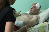 A police officer writes a report as a man wounded by the Russian deadly rocket attack at a shopping centre tells her about the attack in a city hospital in Kremenchuk in Poltava region, Ukraine, Tuesday, June 28, 2022. (AP Photo/Efrem Lukatsky)