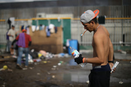 A migrant, part of a caravan of thousands of migrants from Central America trying to reach the United States, cleans his teeth in front of showers at a temporary shelter in Tijuana, Mexico, November 28, 2018. REUTERS/Lucy Nicholson