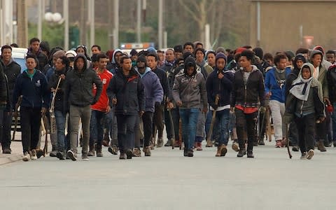 Migrants carrying sticks march in the streets of Calais, northern France, Thursday, Feb. 1, 2018. - Credit:  AP