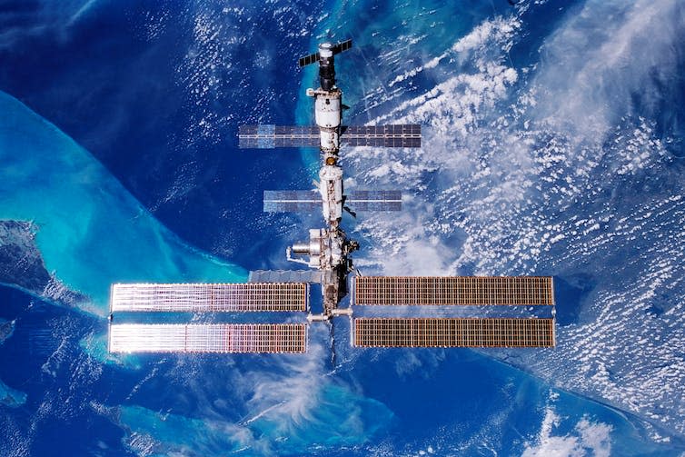 An overhead view of the International Space Station with Earth in the background.