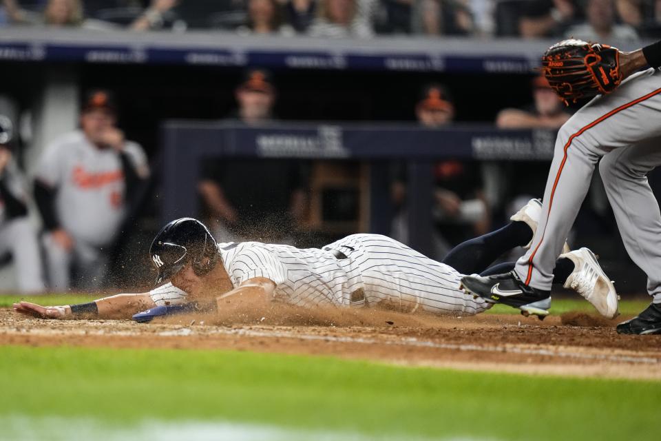 New York Yankees' Anthony Volpe, left, slides past Baltimore Orioles relief pitcher Yennier Cano, right, to score on a wild pitch during the seventh inning of a baseball game Monday, July 3, 2023, in New York. (AP Photo/Frank Franklin II)