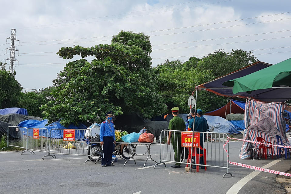 Policemen guard behind barricades set up to control the traffic in Hanoi, Vietnam, Saturday, July 24, 2021. Vietnam announced a 15-day lockdown in the capital Hanoi starting Saturday as a coronavirus surge spread from the southern Mekong Delta region. (AP Photo/Hieu Dinh)