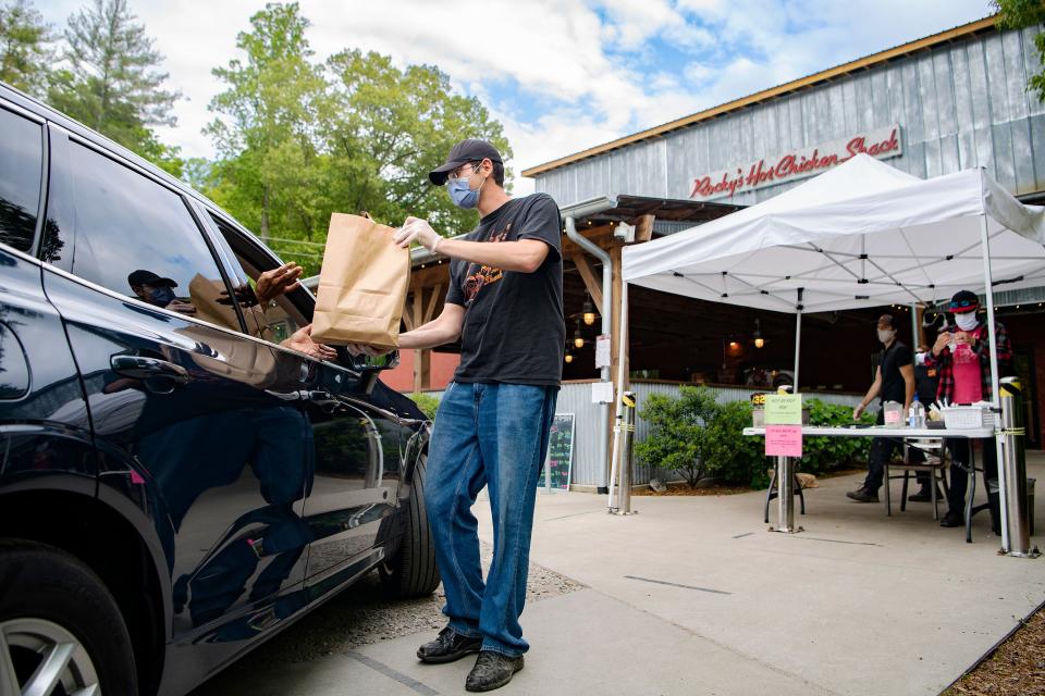 DJ Jackson delivers an order to a car as he works the take-out tent at Rocky's Hot Chicken Shack on Sweeten Creek Road on May 13, 2020. The restaurant is doing carry-out orders only amid state-wide COVID-19 restrictions. 