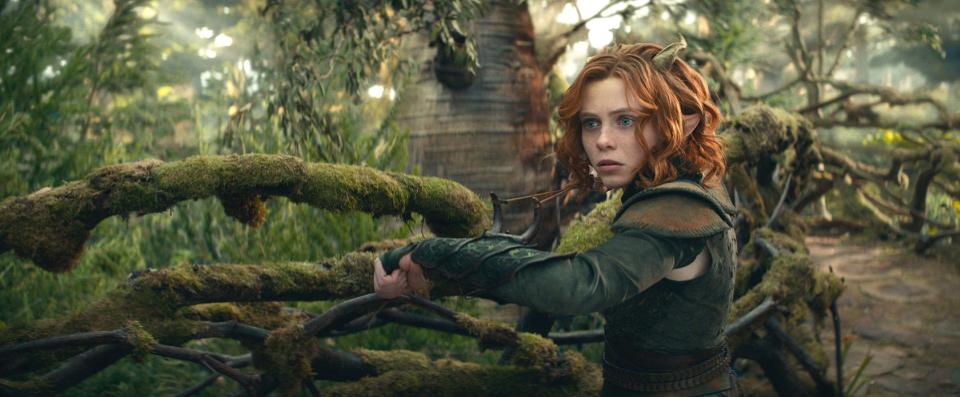 Sophia Lillis stands near a mossy branch in a druid's tree home