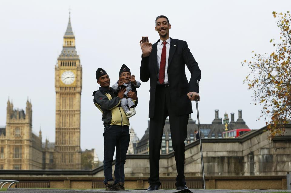The world's shortest man Chandra Bahadur Dangi is held by nephew Dolakh Dangi as they pose with the tallest living man Sultan Kosen to mark the Guinness World Records Day in London
