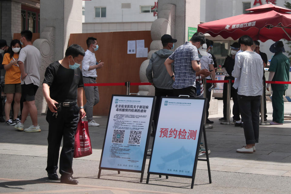 Gente con mascarillas para combatir el contagio del coronavirus se reúne ante un hospital para pedir información sobre pruebas del virus en Beijing, el lunes 15 de junio de 2020. (AP Foto/Andy Wong)