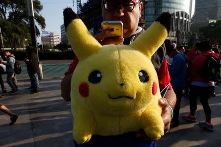 A man carries stuffed toy of a character from Pokemon, Pikachu, as he plays Pokemon Go during a gathering to celebrate "Pokemon Day" in Mexico City August 21, 2016. REUTERS/Carlos Jasso