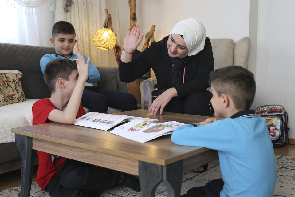 Fatima Alzahra Shon, 32, a Syrian refugee, teaches her children after an interview with The Associated Press in Istanbul, Friday, Sept. 17, 2021. Shon thinks neighbors attacked her and her son Amr, top left, in their Istanbul apartment building because she is Syrian. The 32-year-old refugee from Aleppo was confronted on Sept. 1 by a Turkish woman who asked her what she was doing in "our" country. Shon replied, "Who are you to say that to me?" The situation quickly escalated. (AP Photo/Emrah Gurel)