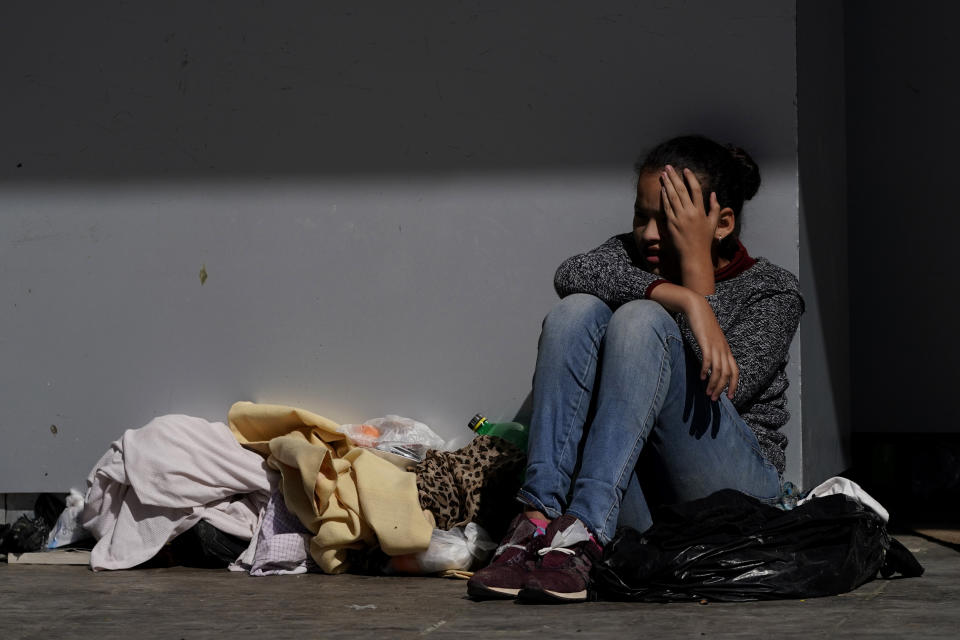 A migrant shields herself from the sun while resting at a plaza near the McAllen-Hidalgo International Bridge point of entry into the U.S., after being caught trying to cross into the U.S. Thursday, March 18, 2021, in Reynosa, Mexico. The fate of thousands of migrant families who have recently arrived at the Mexico border is being decided by a mysterious new system under President Joe Biden. U.S. authorities are releasing migrants with “acute vulnerabilities” and allowing them to pursue asylum. But it’s not clear why some are considered vulnerable and not others. (AP Photo/Julio Cortez)