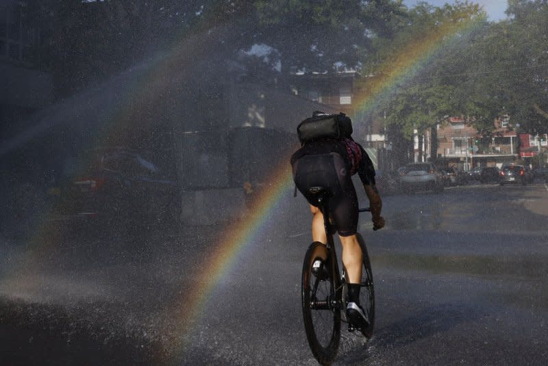 A cyclist goes through splashing water from an opened fire hydrant in dangerously hot weather in New York City July 26. An extreme heat wave has 143 million people in 19 U.S. states under heat alerts. . Photo by John Angelillo/UPI