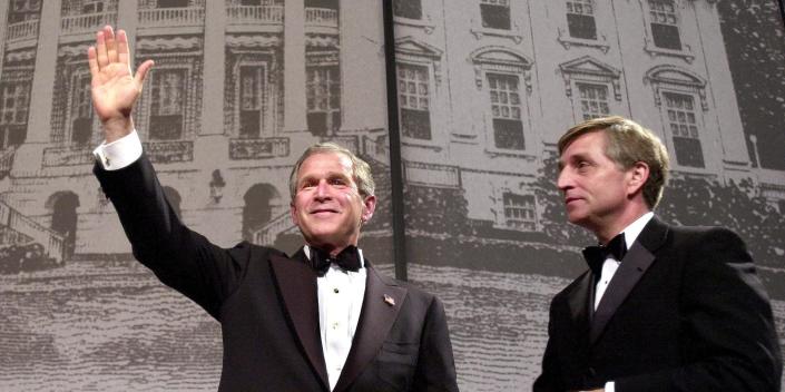 Former President George W. Bush waves next to Marc Racicot