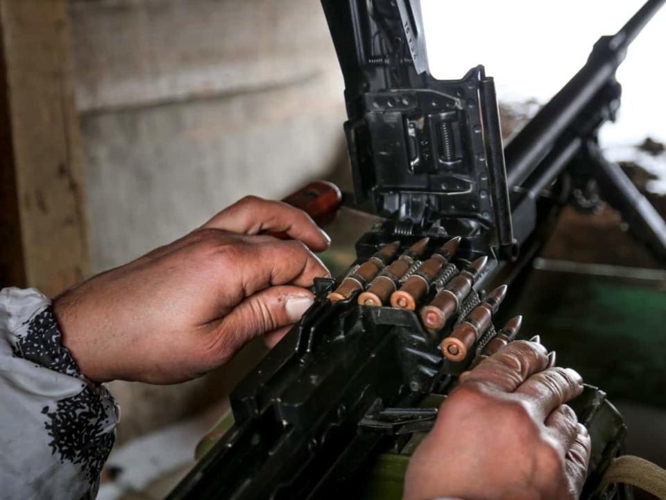 A fighter prepares his machine-gun in a shelter on the territory controlled by pro-Russian militants at the frontline with Ukrainian government forces in Slavyanoserbsk, Luhansk region, eastern Ukraine, on Jan. 25, 2022. (Alexei Alexandrov/AP - image credit)