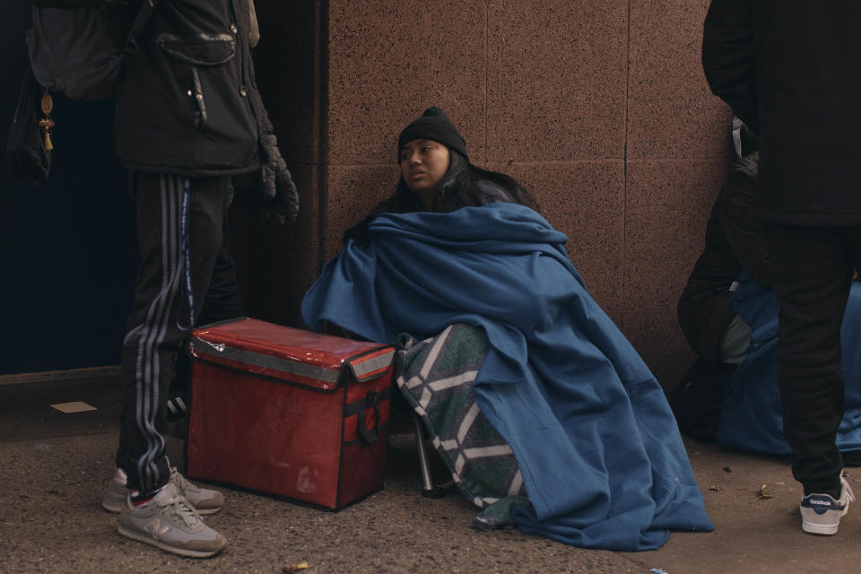 Migrants queue in the cold as they look for a shelter outside a migrant assistance center at St. Brigid Elementary School on Tuesday, Dec. 5, 2023, in New York. It could be a cold, grim New Year for thousands of migrant families living in New York City’s emergency shelter system. With winter setting in, they are being told they need to clear out, with no guarantee they’ll be given a bed elsewhere. (AP Photo/Andres Kudacki)