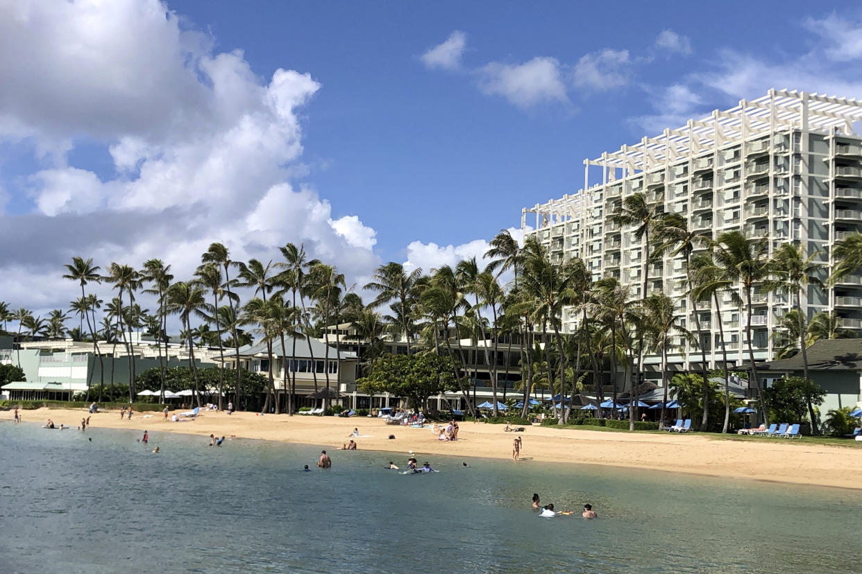 FILE - In this Sunday, Nov. 15, 2020, file photo, people are seen on the beach and in the water in front of the Kahala Hotel & Resort in Honolulu. As Hawaii struggles to control COVID-19 as the highly contagious delta variant spreads, Gov. David Ige is asking people not to visit the islands and he wants visitors and residents to limit travel to essential purposes. (AP Photo/Jennifer Sinco Kelleher, File)