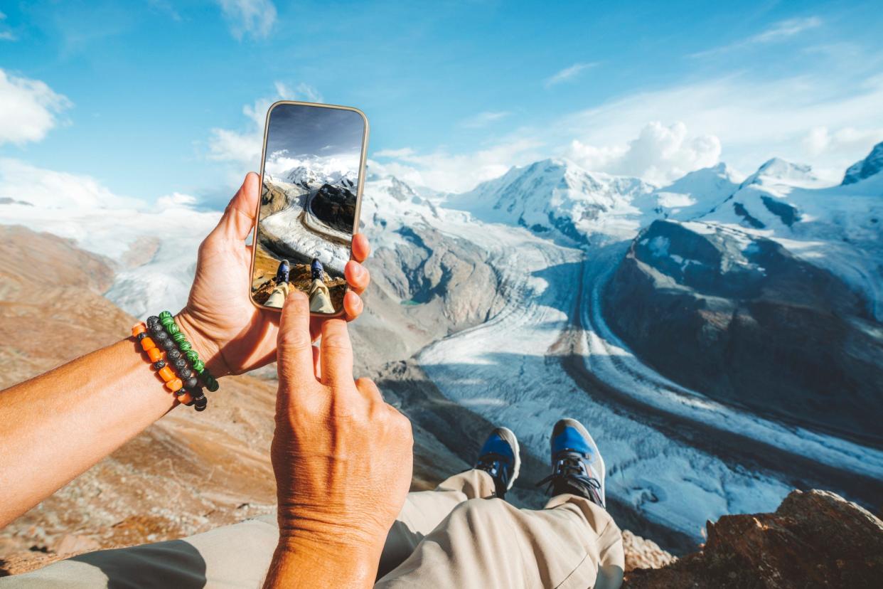 A stock image shows a tourist photographing the Gorner Glacier in Switzerland.