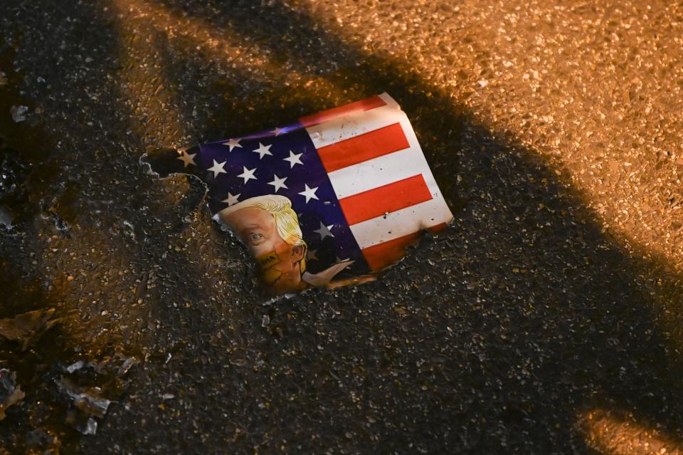 A poster showing the US flag and the face of US President Donald Trump is seen burnt on the street after anti-Trump demonstrators set it on fire in Black Lives Matter Plaza in Washington, DC on November 14, 2020. (Photo by Roberto SCHMIDT / AFP) (Photo by ROBERTO SCHMIDT/AFP via Getty Images)