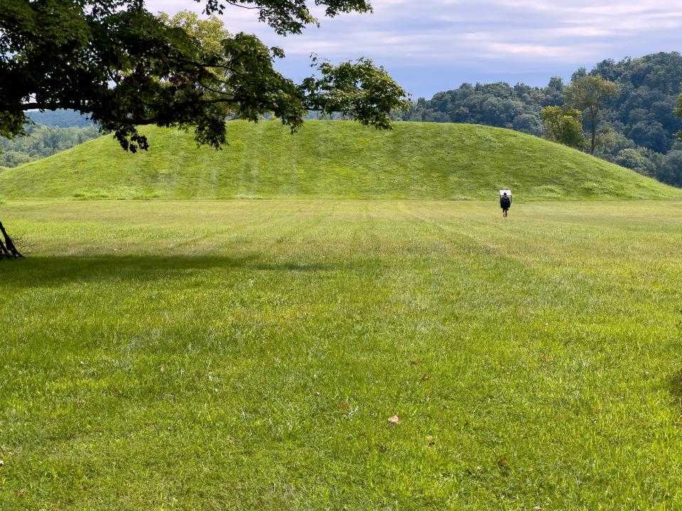 Person walks toward a prehistoric earthwork burial mound
