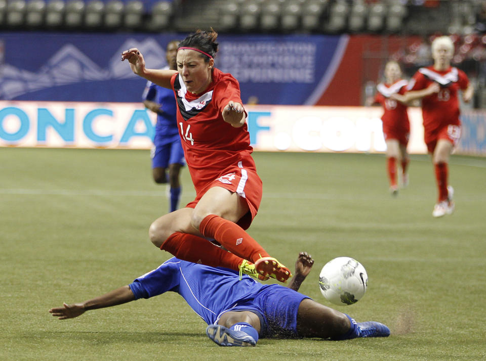 VANCOUVER, CANADA - JANUARY 19: Melissa Tancredi #14 of Canada evades a slide tackle by Carmela Aristilde #3 of Haiti during the 2012 CONCACAF Women's Olympic Qualifying Tournament at BC Place on January 19, 2012 in Vancouver, British Columbia, Canada. (Photo by Jeff Vinnick/Getty Images)